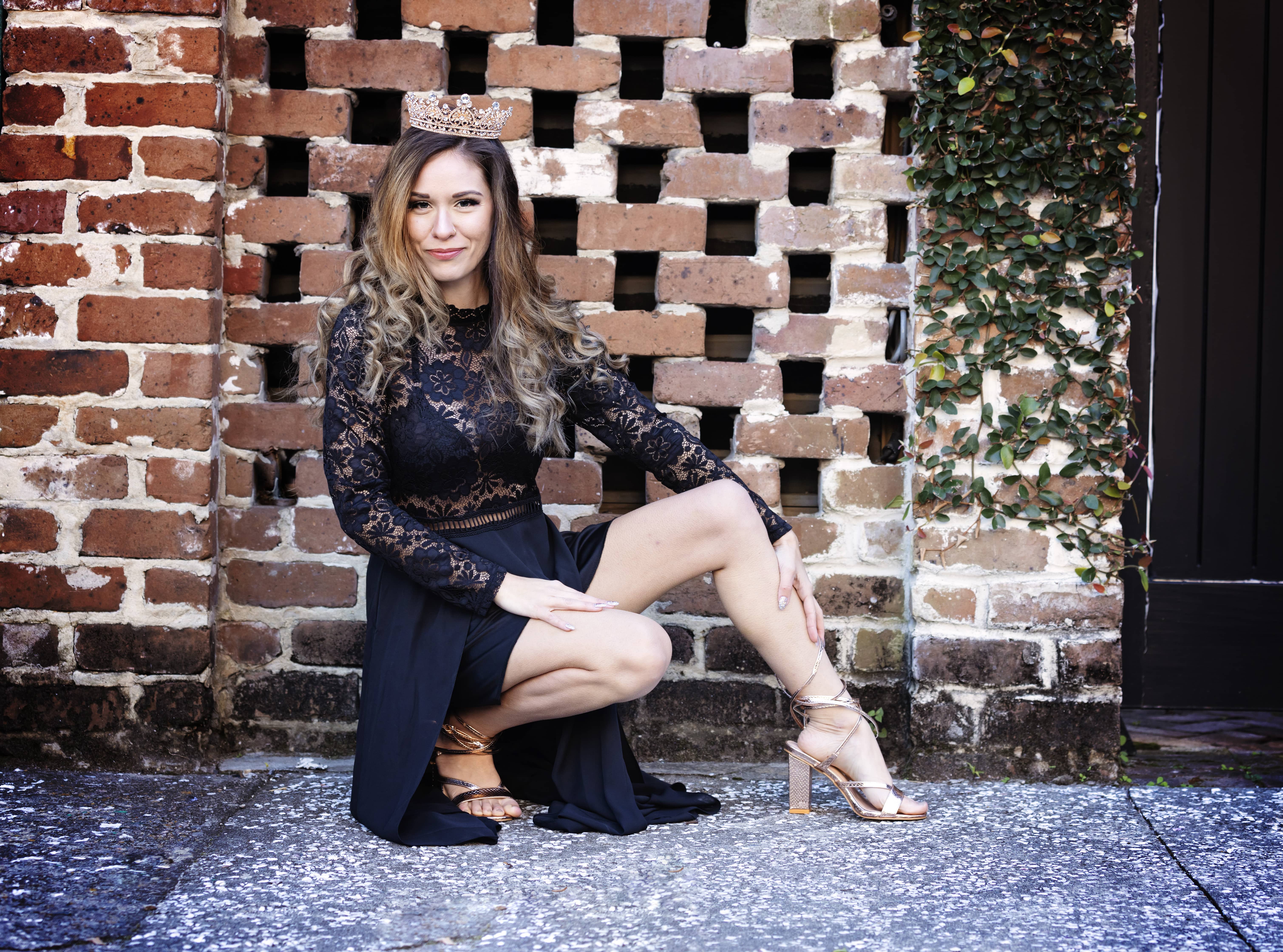 Woman kneeling next to a brick wall
