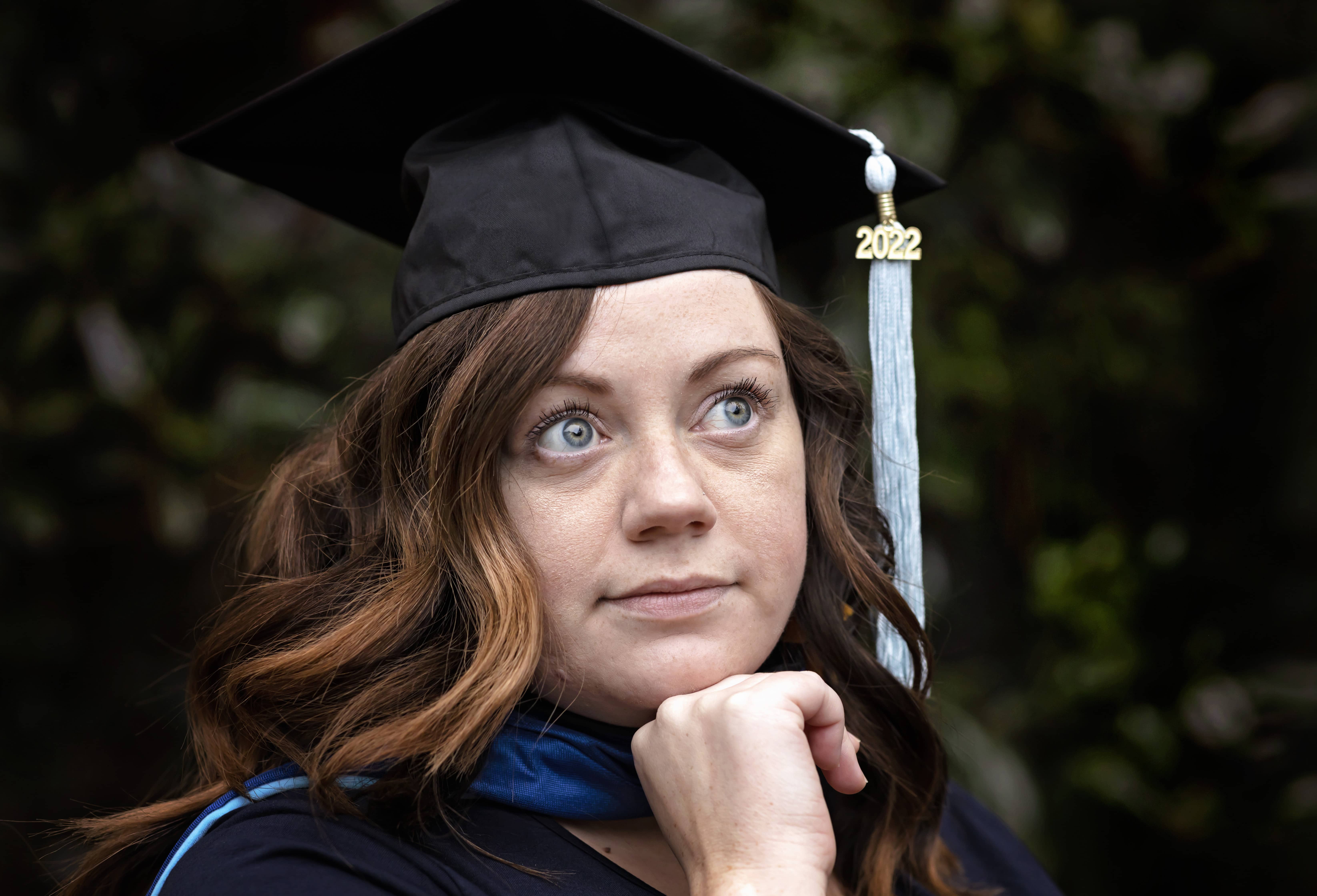 Graduate poses in their graduation robes