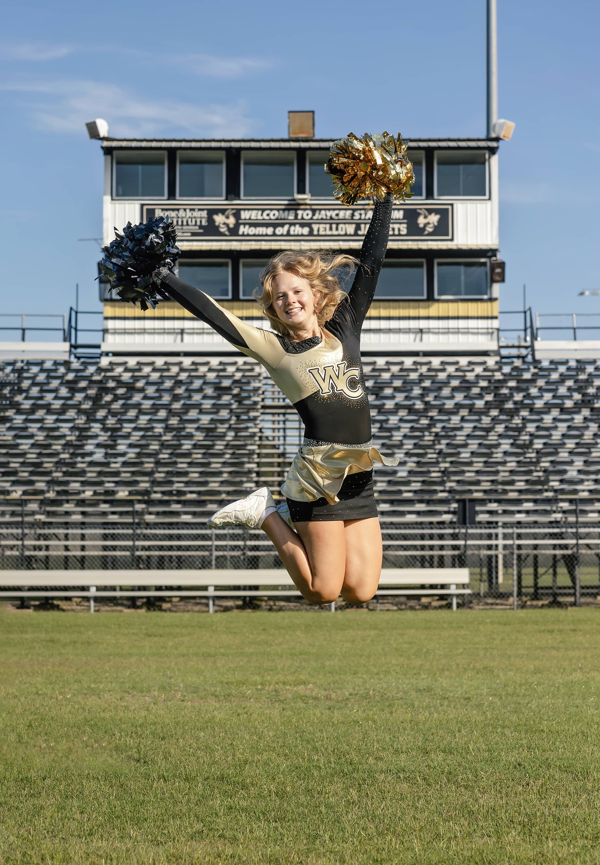 Cheerleader jumping with pom poms